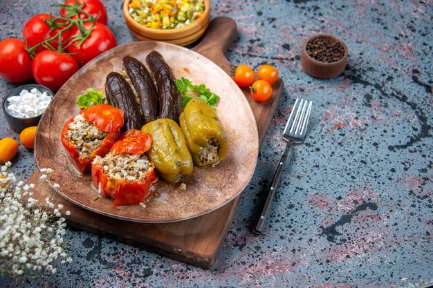 Vista frontal dolma de verduras deliciosas con ensalada y tomates sobre fondo azul.