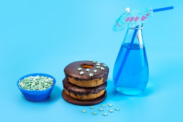 Una vista frontal de donas de chocolate con azul, bebida en azul, color de galleta de pastel de azúcar