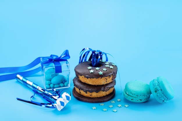 Una vista frontal de donas de chocolate junto con azul, macarons franceses y caramelos en azul, color de galleta de pastel dulce de caramelo