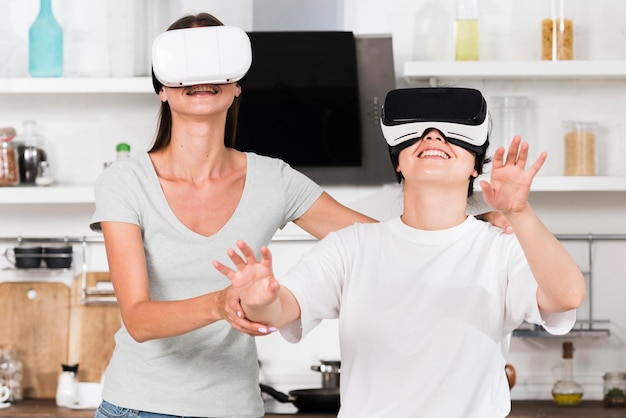 Foto gratuita vista frontal de dos amigos en casa divirtiéndose con casco de realidad virtual