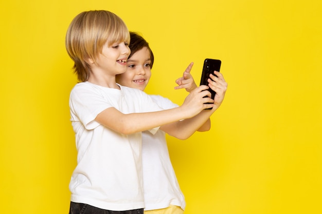 Vista frontal dos chicos adorables lindo tomando selfie sonriendo en amarillo