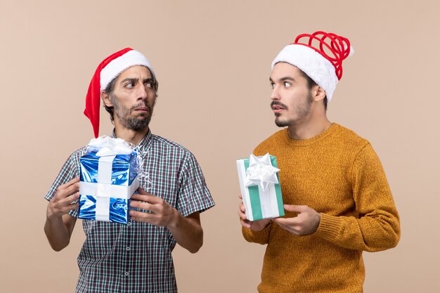 Vista frontal de dos chicos confundidos con gorro de Papá Noel y mirando el uno al otro