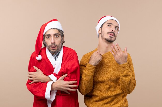 Vista frontal de dos chicos de Navidad, uno con abrigo de santa frío y el otro caliente sobre fondo beige aislado