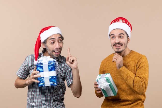 Vista frontal de dos chicos de Navidad hablando entre sí y sosteniendo regalos de Navidad