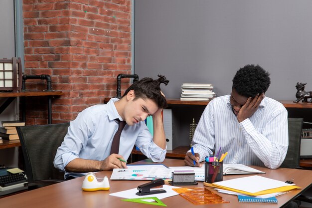 Vista frontal de dos empresarios cansados trabajando juntos