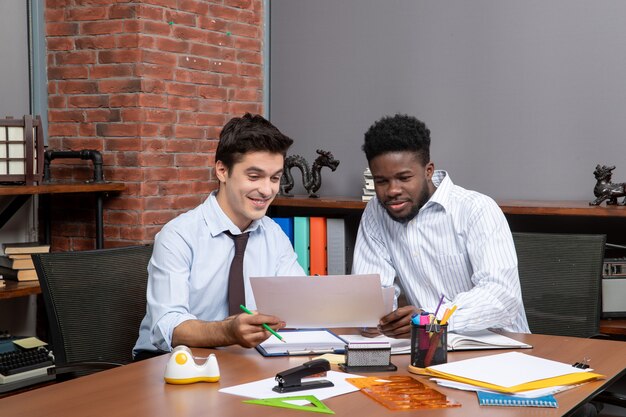 Vista frontal de dos empresarios felices que satisfacen trabajar juntos en la oficina