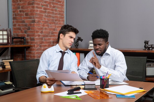 Vista frontal de dos empresarios incansables discutiendo el proyecto en el trabajo