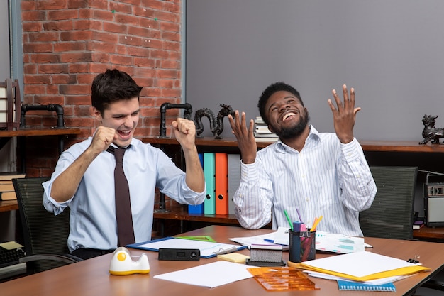 Vista frontal de dos gerentes de negocios mostrando gesto ganador