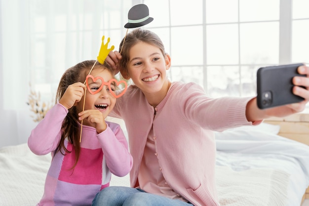 Vista frontal de dos hermanas en casa tomando selfie