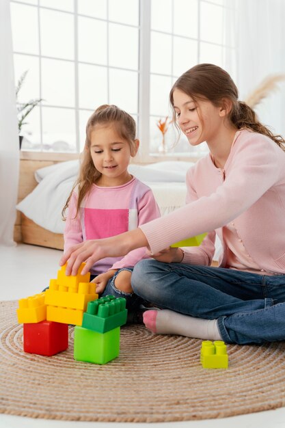 Vista frontal de dos hermanas jugando con juguetes en casa