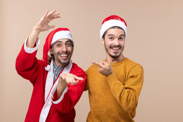 Vista frontal de dos hombres uno mirando a la cámara con cara feliz sobre fondo beige aislado