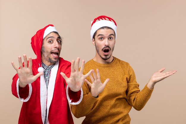 Vista frontal de dos hombres sorprendidos abriendo sus manos sobre fondo beige aislado