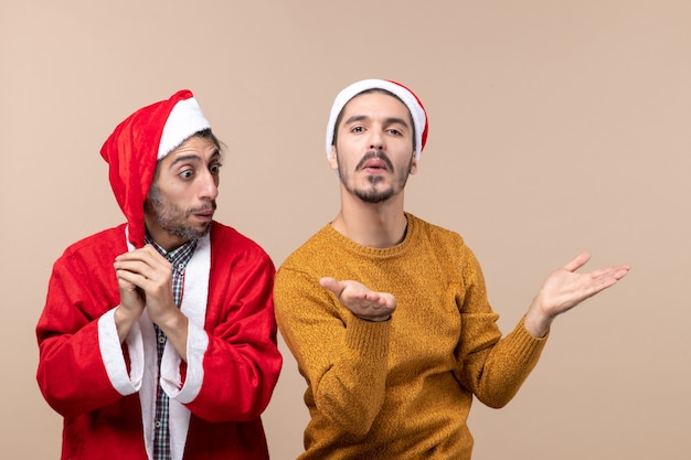 Foto gratuita vista frontal de dos hombres sorprendidos uno haciendo signo de besos sobre fondo beige aislado