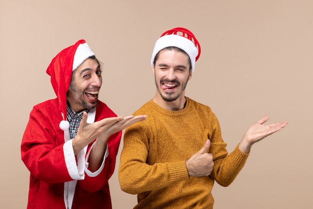 Vista frontal de dos hombres sorprendidos mostrando algo sobre fondo beige aislado