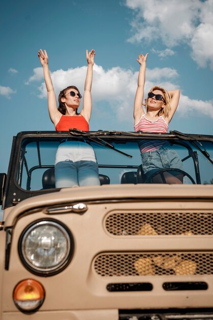 Vista frontal de dos mujeres divirtiéndose mientras viaja en coche