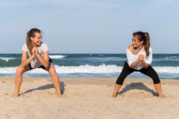 Vista frontal, de, dos mujeres, ejercitar, en la playa