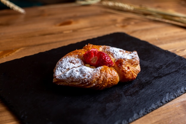 Una vista frontal dulce bagel con azúcar en polvo sobre el tejido negro delicioso delicioso aislado en la galleta de azúcar de escritorio marrón