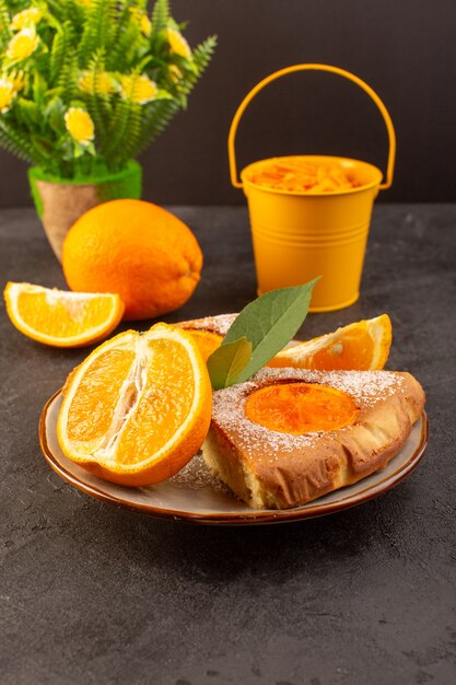 Una vista frontal dulce pastel de naranja dulce deliciosas rebanadas de pastel junto con rodajas de naranja dentro de la placa redonda sobre el fondo gris galleta de azúcar dulce