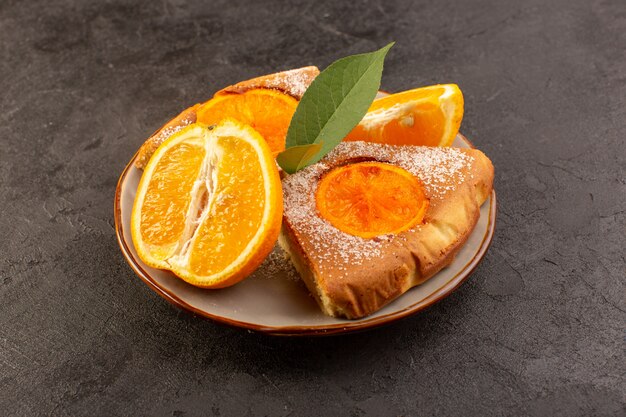 Una vista frontal dulce pastel de naranja dulce deliciosas rebanadas de pastel junto con rodajas de naranja dentro de la placa redonda sobre el fondo gris galleta de azúcar dulce