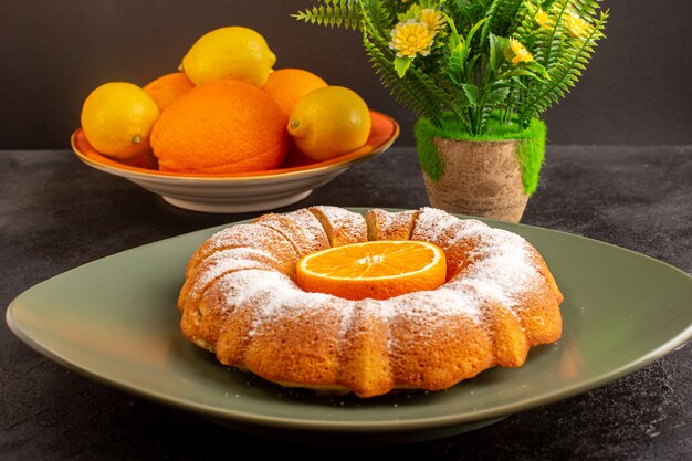 Una vista frontal dulce pastel redondo con azúcar en polvo y en rodajas dulce delicioso plato interior junto con flores y limones en el fondo gris galleta galleta de azúcar