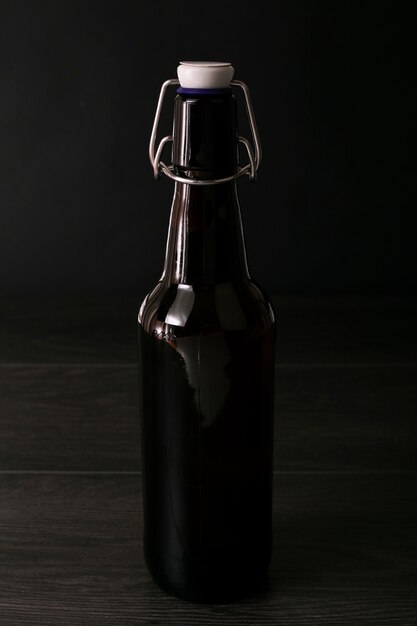 Vista frontal elegante botella de cerveza sobre fondo oscuro