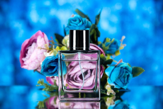 Vista frontal de la elegante botella de perfume flores sobre fondo azul.