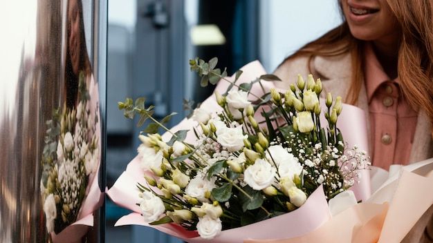 Vista frontal de la elegante mujer sosteniendo un ramo de flores fuera