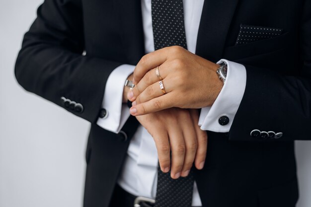 Vista frontal del elegante traje negro del hombre y la mano del hombre sostiene reloj