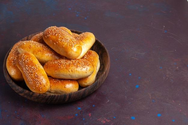 Vista frontal empanadas dulces deliciosa masa horneada para té en el escritorio oscuro