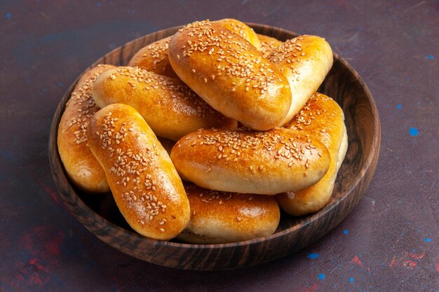 Vista frontal empanadas dulces deliciosa masa horneada para té en el espacio oscuro