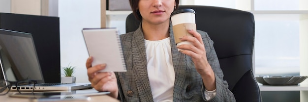 Vista frontal de la empresaria en la oficina tomando café