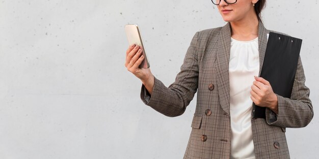 Vista frontal de la empresaria con smartphone y Bloc de notas al aire libre