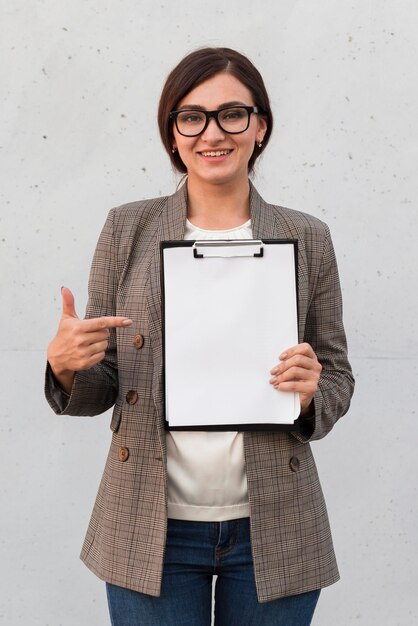 Vista frontal de la empresaria sonriente apuntando al bloc de notas