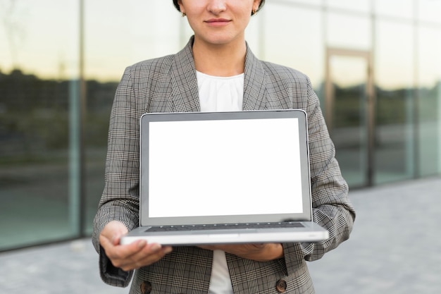 Foto gratuita vista frontal de la empresaria sosteniendo portátil al aire libre