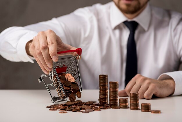 Vista frontal del empresario derramando carrito de compras de monedas