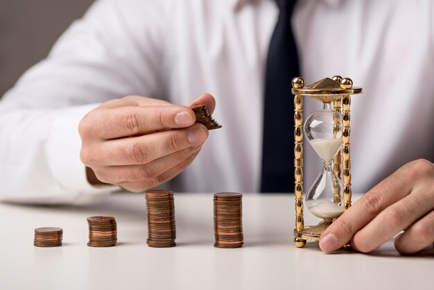 Vista frontal del empresario con monedas y reloj de arena