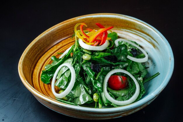 Vista frontal ensalada de verduras con cebolla tomates y pimientos en un plato