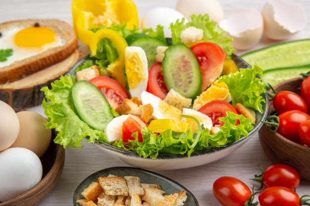 Vista frontal ensalada de verduras con huevos y condimentos sobre fondo blanco comida madura comida desayuno color ensalada almuerzo