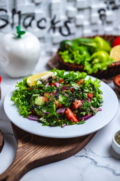 Vista frontal ensalada de verduras con verduras y una rodaja de limón