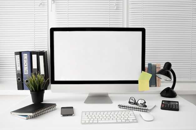 Vista frontal del espacio de trabajo con lámpara y pantalla de computadora