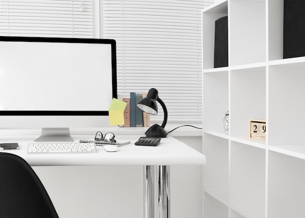 Vista frontal del espacio de trabajo con pantalla de computadora y lámpara
