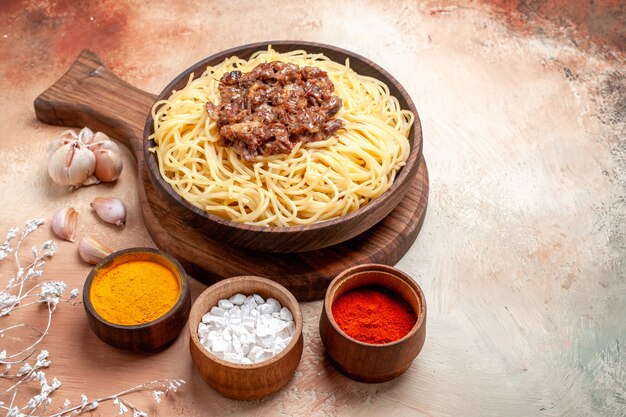 Vista frontal de espaguetis cocidos con carne molida en el escritorio de madera condimento de plato de masa de pasta