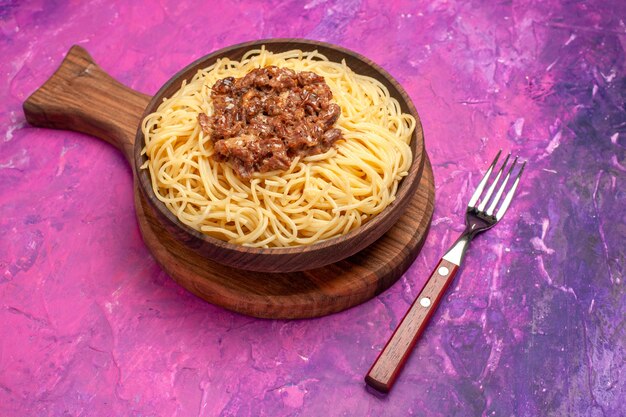 Vista frontal de espaguetis cocidos con carne molida en el plato de masa de mesa rosa condimentos de pasta