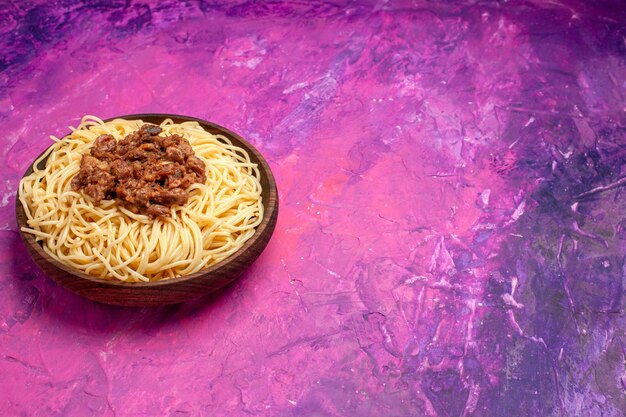 Foto gratuita vista frontal de espaguetis cocidos con carne molida sobre una mesa de color rosa claro plato de masa de color de pasta