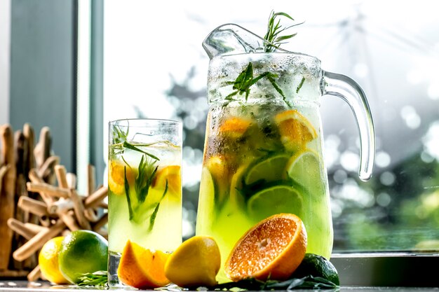 Vista frontal estimulante limonada con limón, lima, naranja y estragón