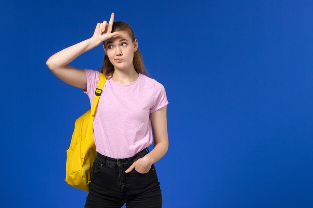 Vista frontal de la estudiante en camiseta rosa con mochila amarilla