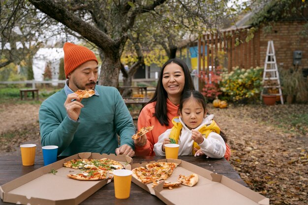 Foto gratuita vista frontal familia comiendo pizza al aire libre