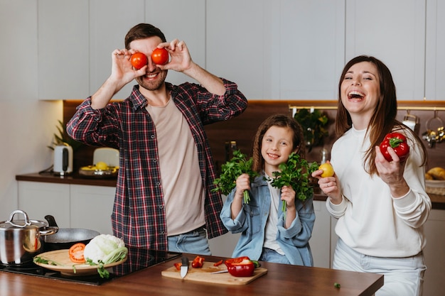 Foto gratuita vista frontal de la familia divirtiéndose mientras prepara la comida en la cocina