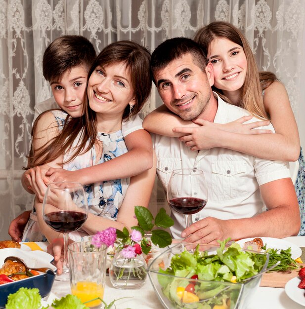 Vista frontal de la familia feliz en la mesa con vino