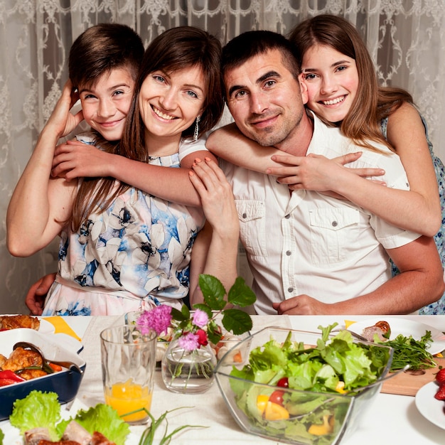 Vista frontal de la familia feliz posando en la mesa